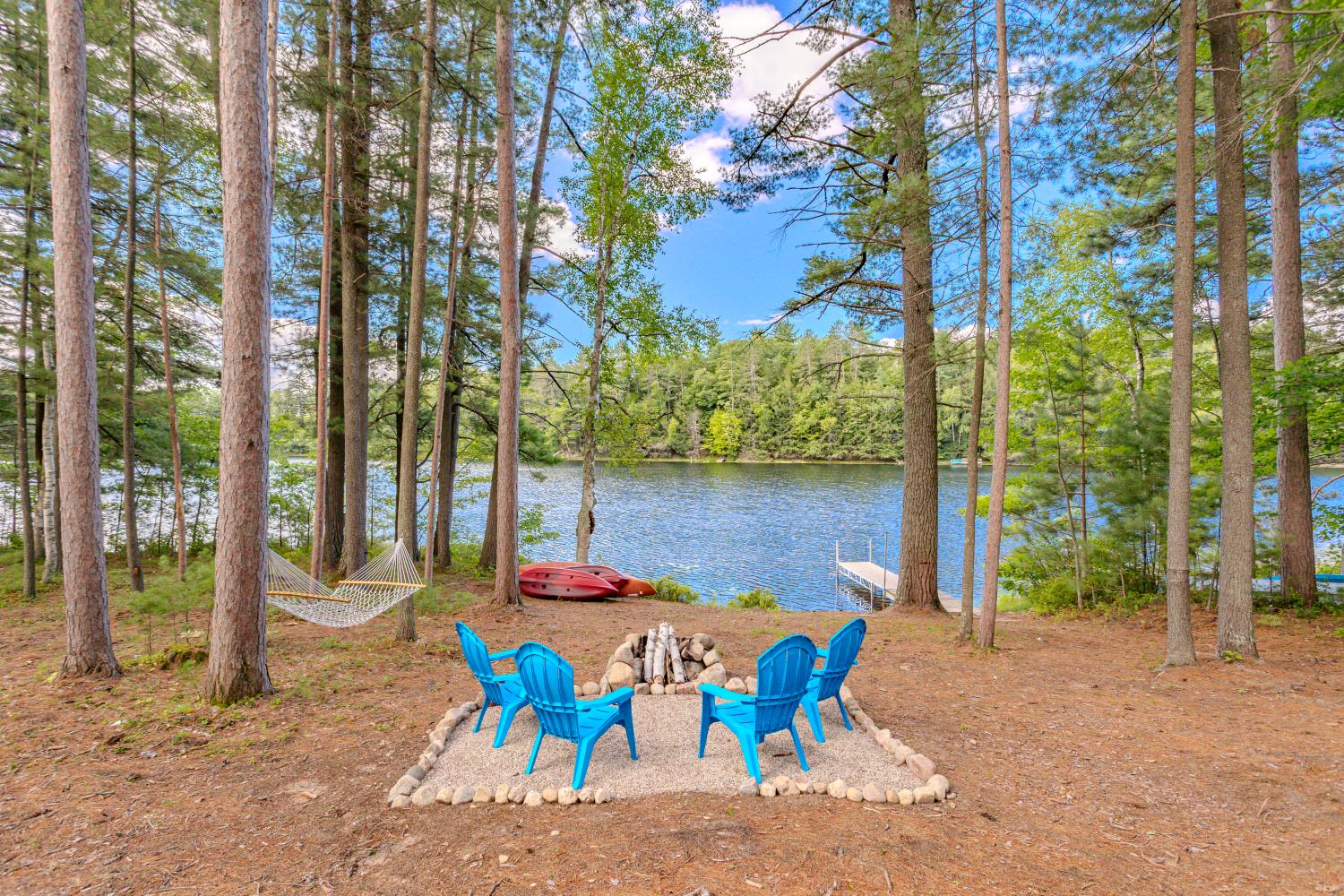 Chairs around a stone fire ring under the pines