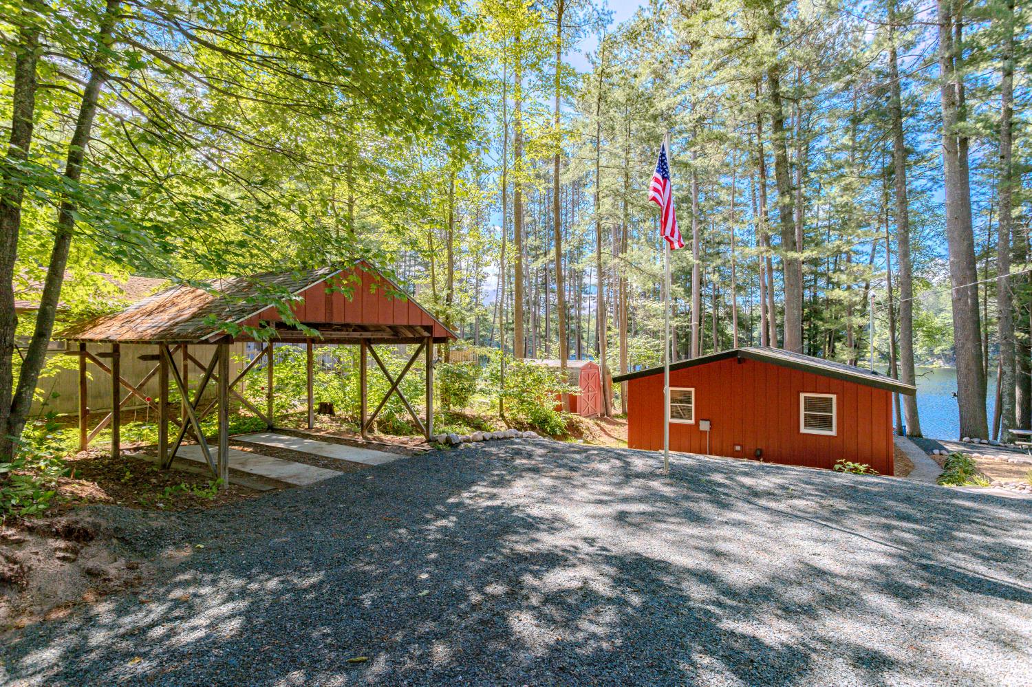 Timber pavilion in the clearing with the cabin behind