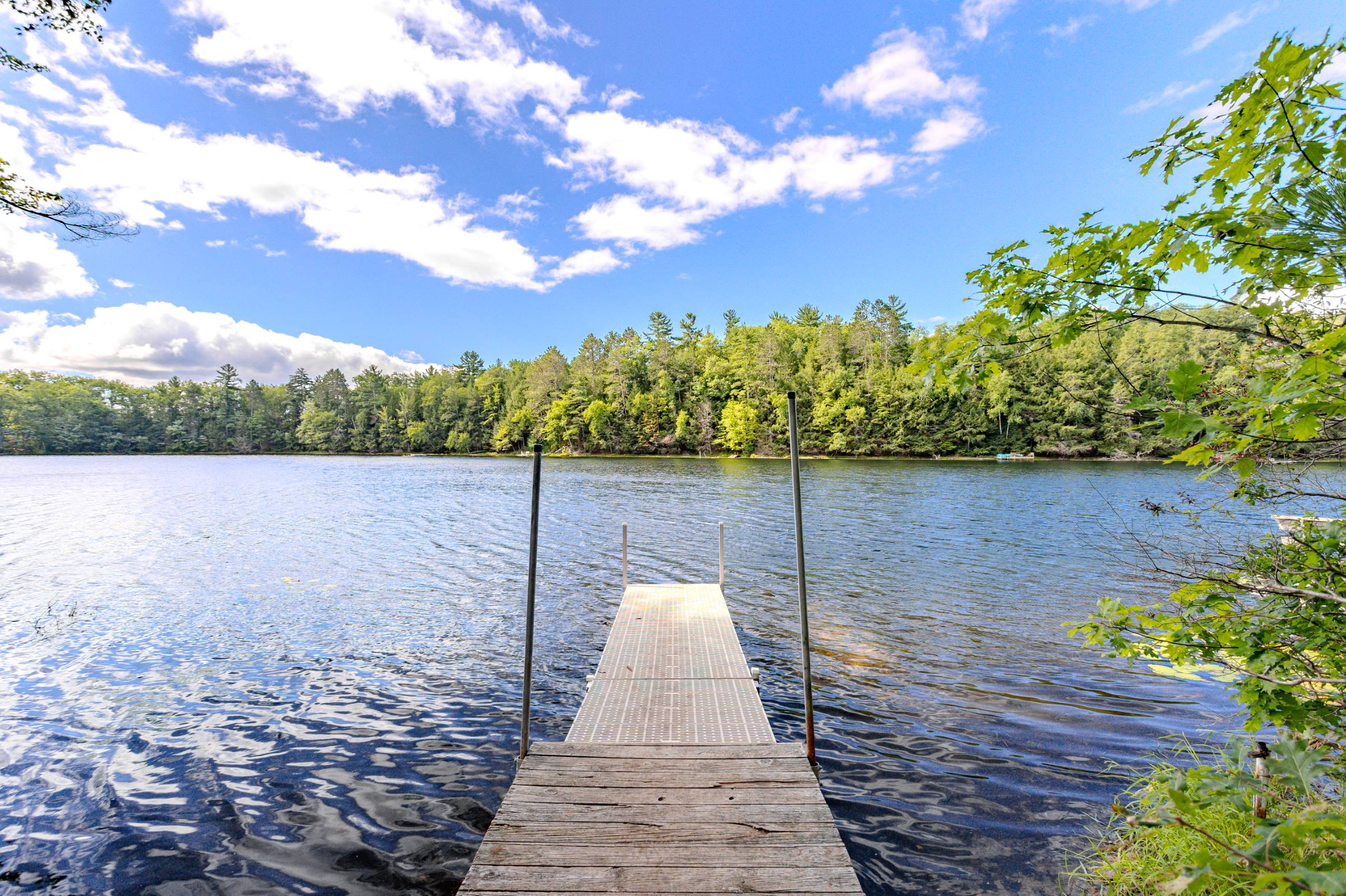 An empty pier reaching into a still Northwoods lake