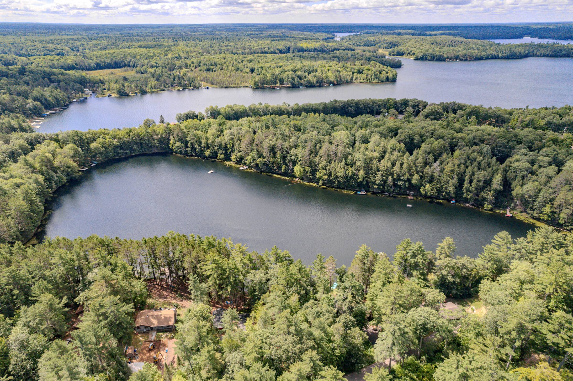 A Northwoods lake wrapped in forest, seen from the air